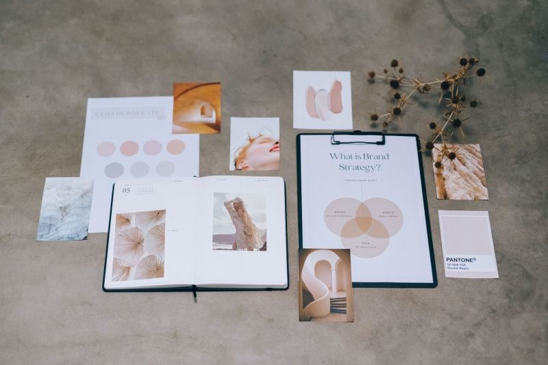 Materiały do pracy nad marką: otwarty notes, karta strategii, fotografie referencyjne i paleta kolorów.